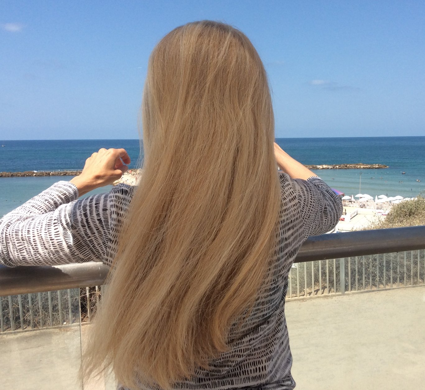 A Suisse client with long, full, natural-looking hair, facing the sea